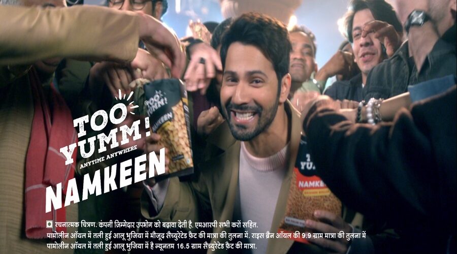 Varun Dhawan, brand ambassador, Too Yumm, Traditional Indian Namkeen range, Palm Oil, digital campaign, Namkeen ke Shaukeen, Aloo Bhujia, Bikaneri Bhujia, Moong Dal, Rice Bran Oil, healthier snacking, guilt-free, innovative offerings, FMCG, RP-Sanjiv Goenka Group, market disruptor, tasty, healthy, innovative, no compromise on taste, Indian snacks, film director, creative agency, Dharma 2.0, Mullen, retail stores, snacking segment, market opportunities, consumer preferences, advertising campaign, product launch, marketing strategy, celebrity endorsement, traditional taste, fun and quirky, mass appeal, production quality, palm oil alternatives, digital first campaign, influencer marketing, informed choice, revolutionize, Indian consumers, healthier options, food industry, Namkeen category, pack sizes, availability, consumer engagement, product differentiation, market penetration, disruptive marketing, healthier lifestyle, guilt-free indulgence, snack market, Namkeen enthusiasts, memorable advertising, popular variants, brand exposure.